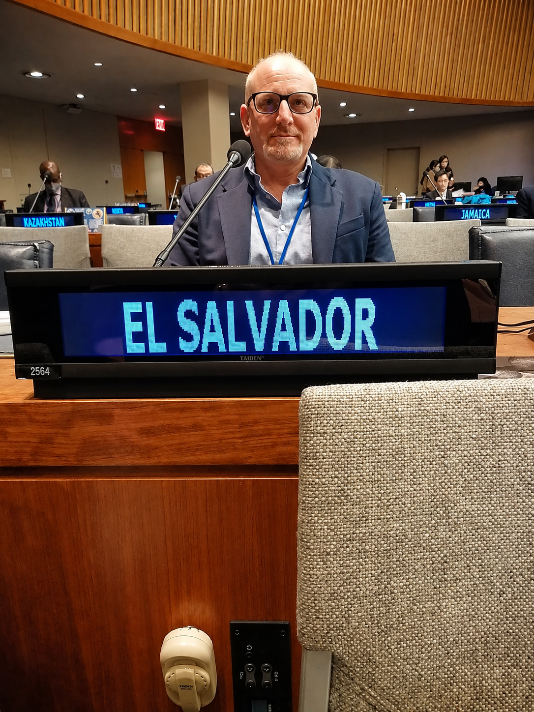Alex Hasbun seated behind the El Salvador display at a United Nations meeting