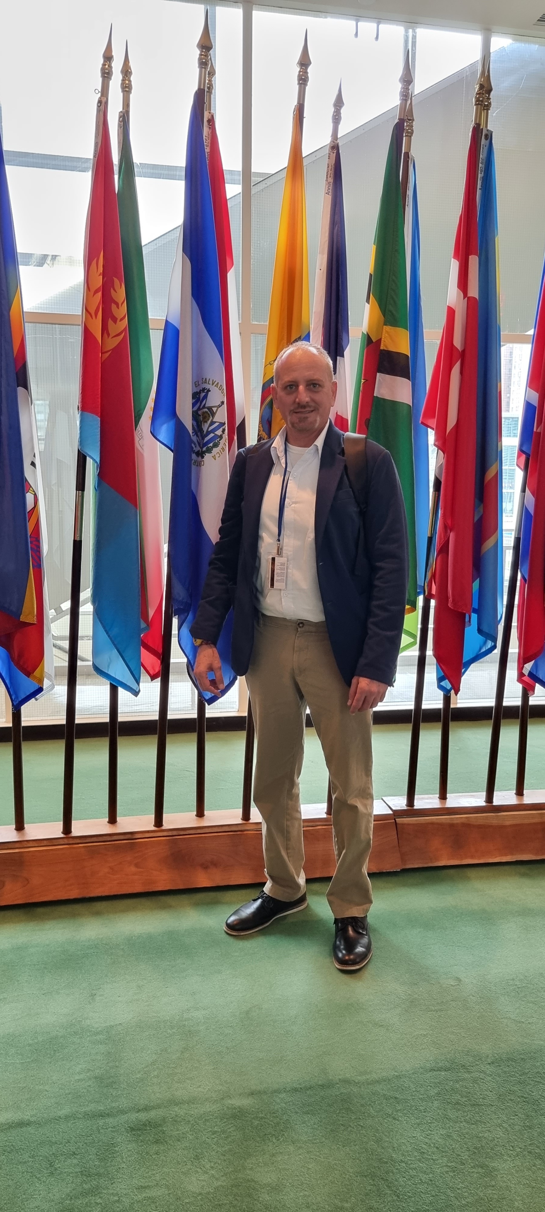 Alex Hasbun standing with international flags at the United Nations